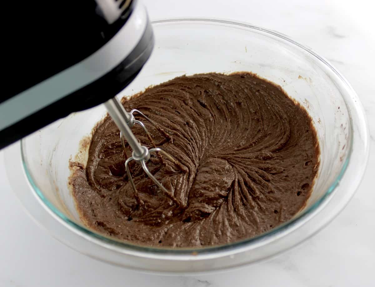 Keto Fudge Brownie batter being mixed with hand mixer in glass bowl