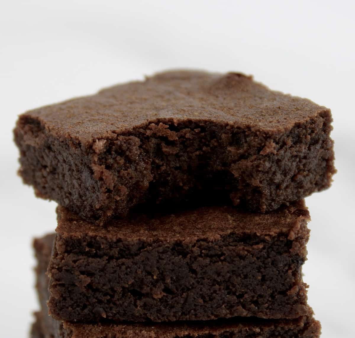Keto Fudge Brownies stacked with bite taken out of top one