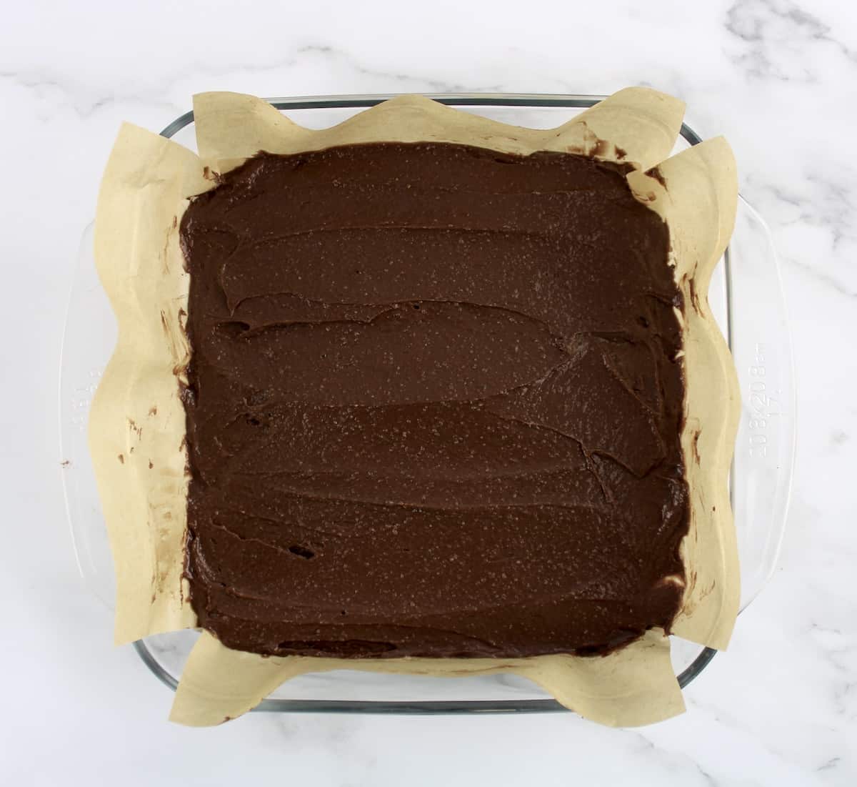 Keto Fudge Brownie batter in glass baking dish lined with parchment