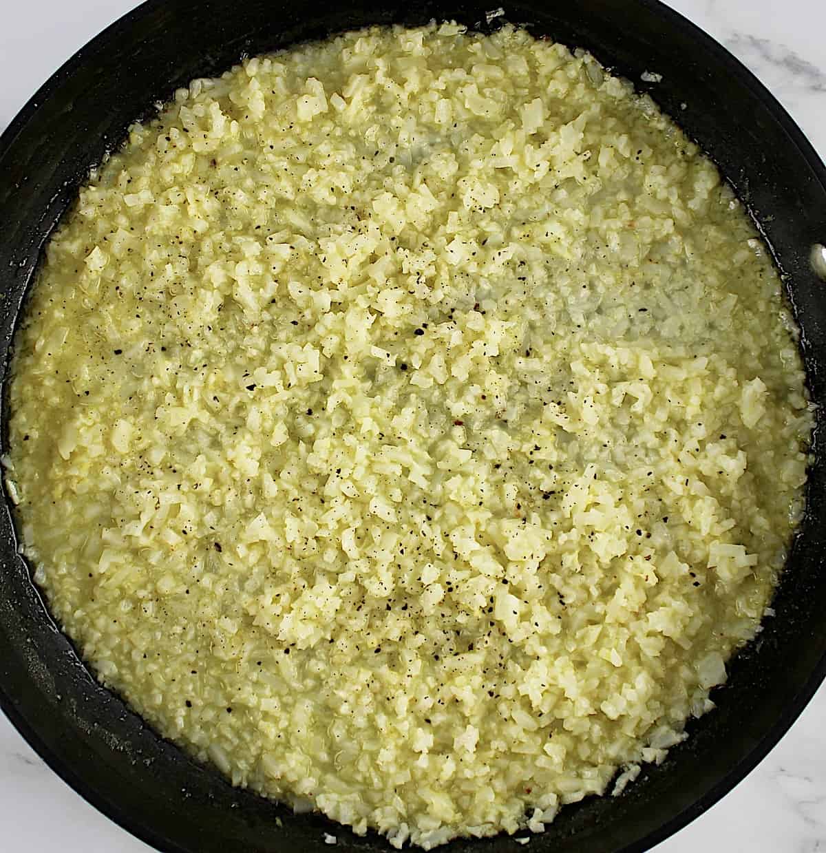cauliflower rice cooking in skillet with scampi sauce