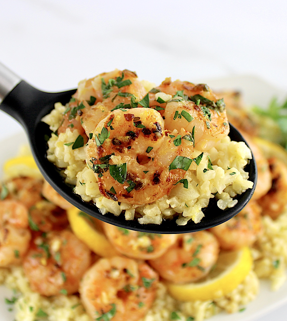 Shrimp Scampi with Cauliflower Rice held up with black serving spoon
