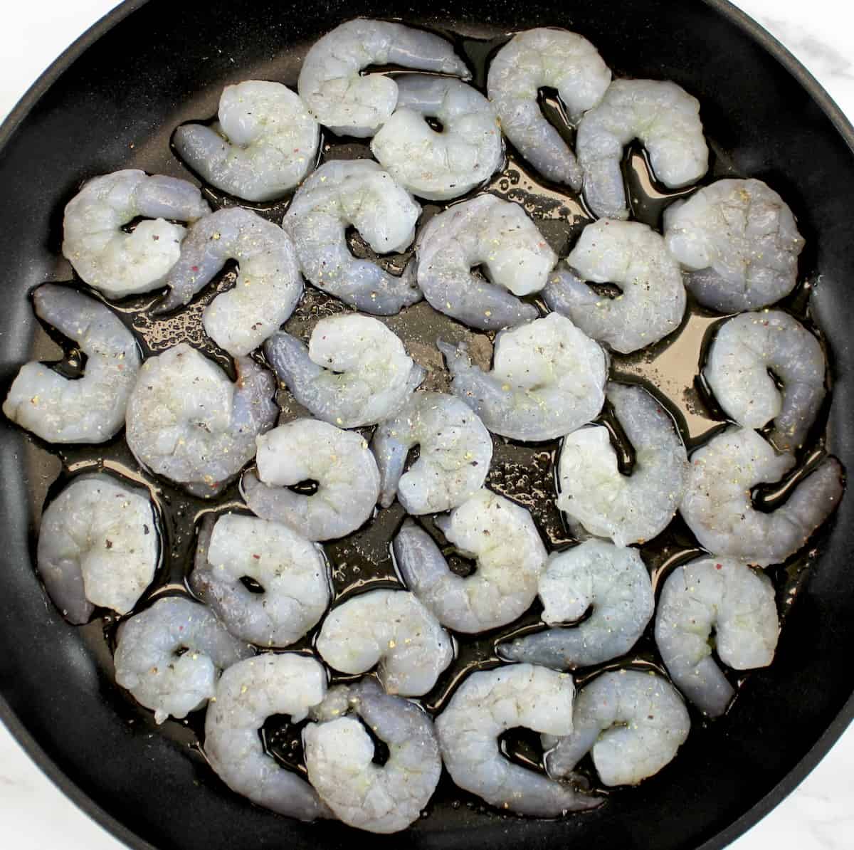 raw shrimp in skillet with olive oil, salt and pepper