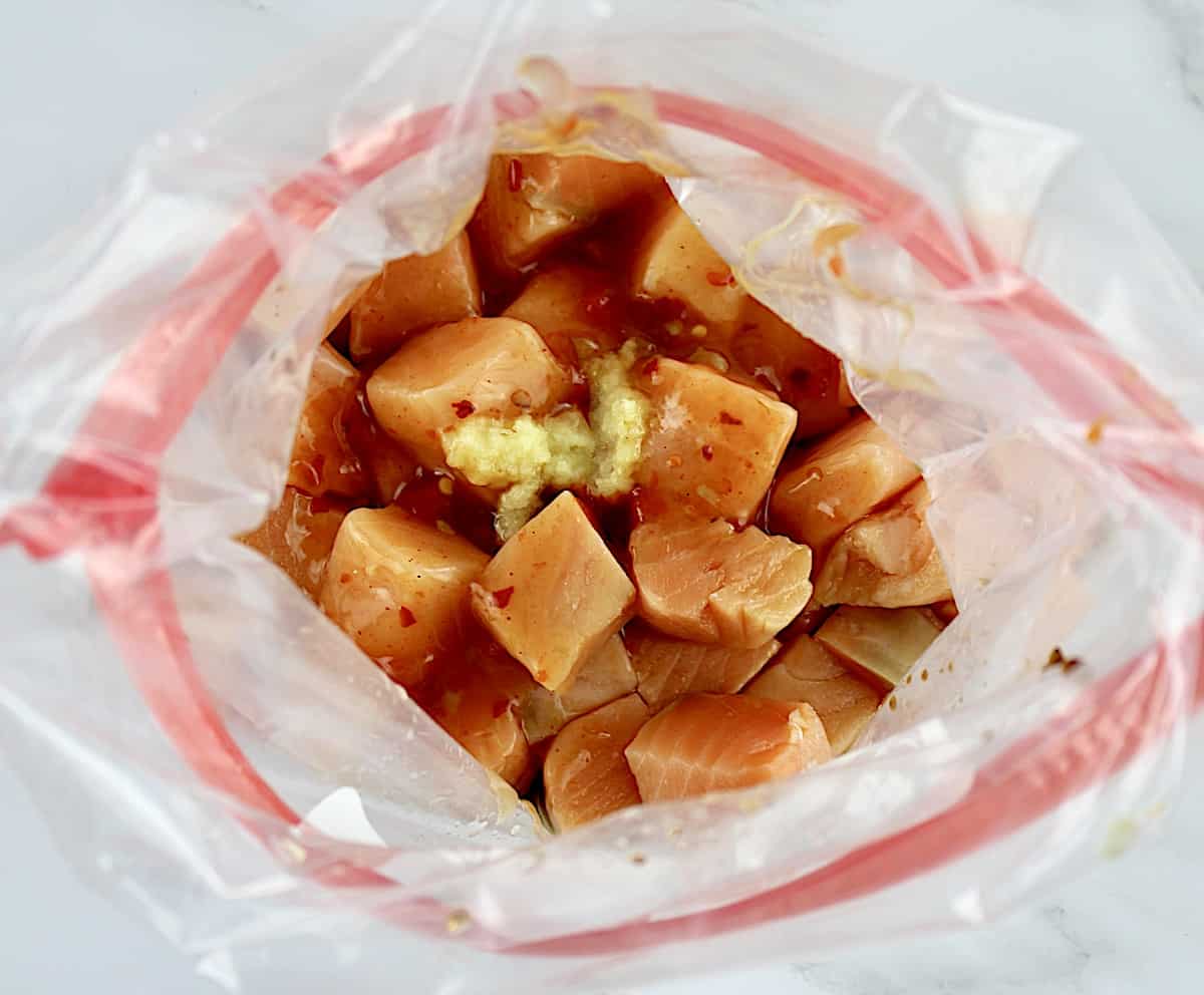salmon bites in food storage bag with sauce and crushed garlic