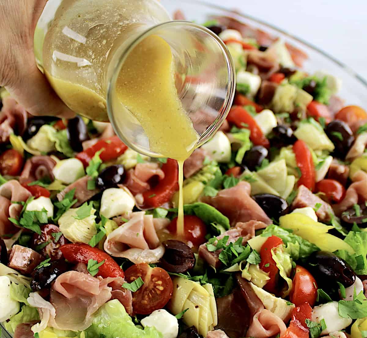 Antipasto Salad with dressing being poured on top