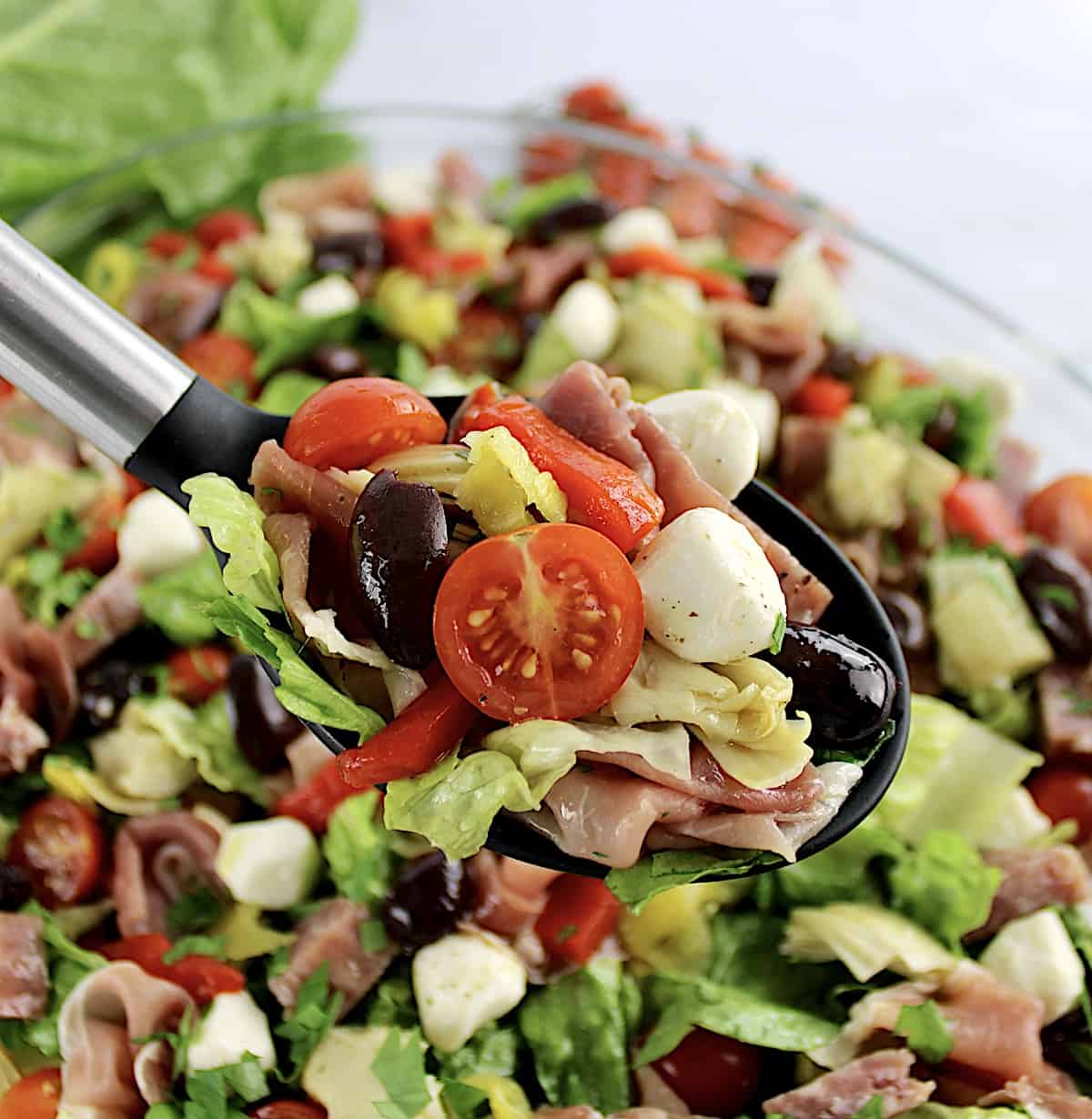 Antipasto Salad in black serving spoon over salad