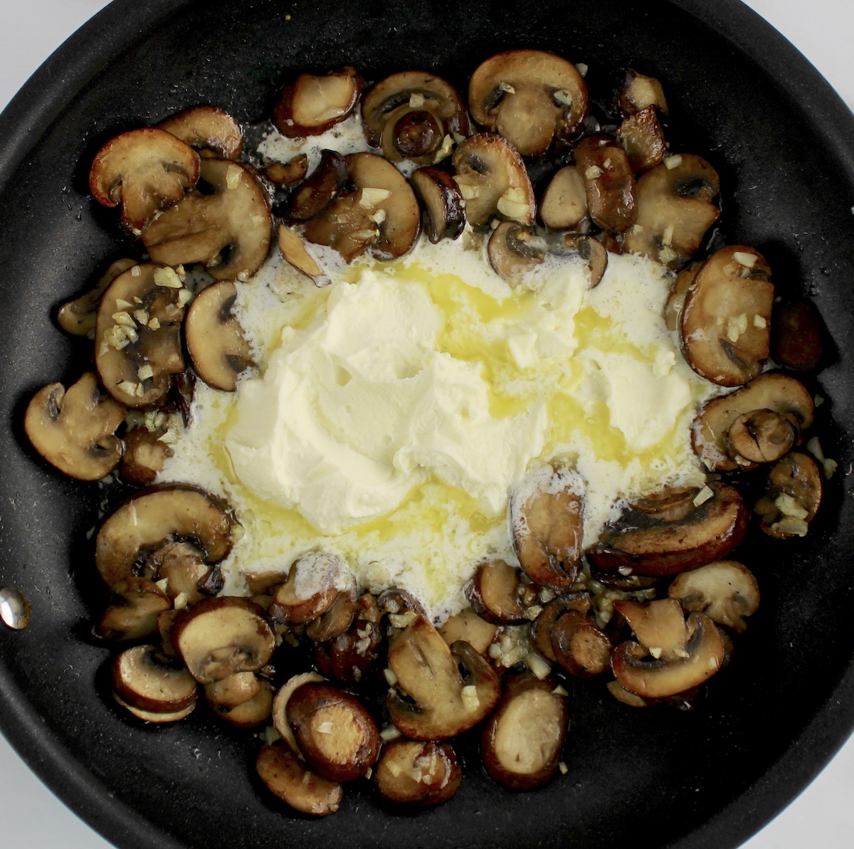 sauteed mushrooms with melted mascarpone cheese in middle of skillet