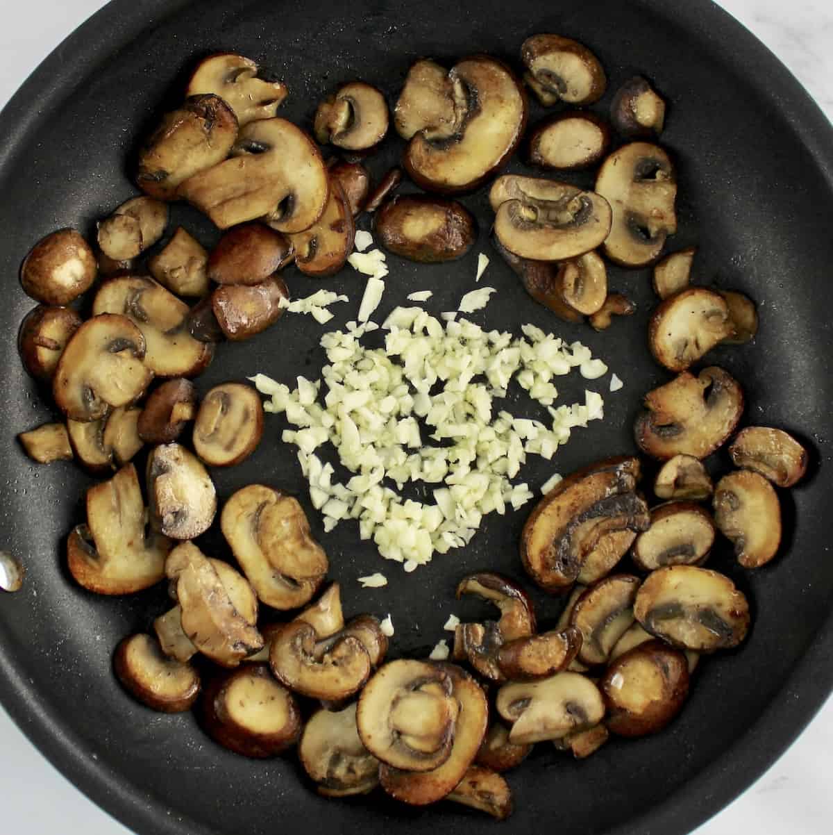 sauteed mushrooms with minced garlic in skillet