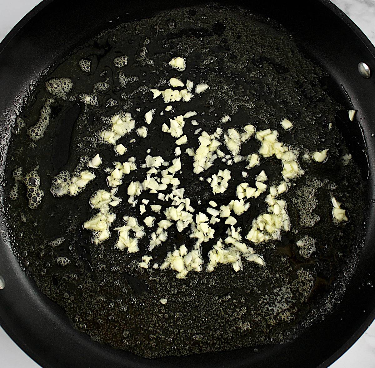 minced garlic being sauteed in skillet