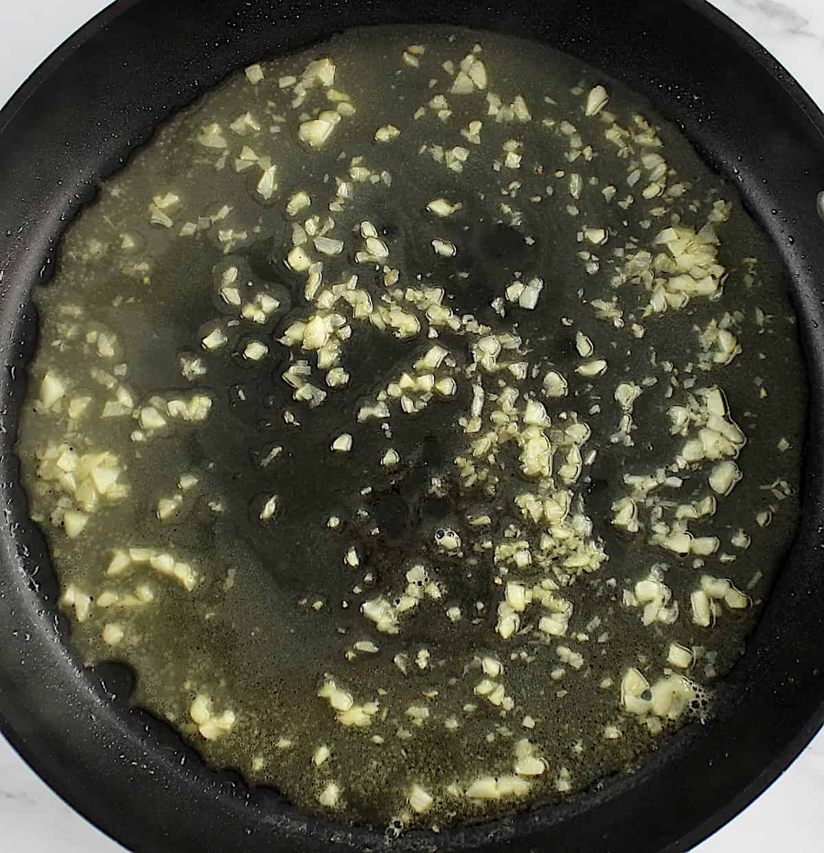 minced garlic and white wine in skillet