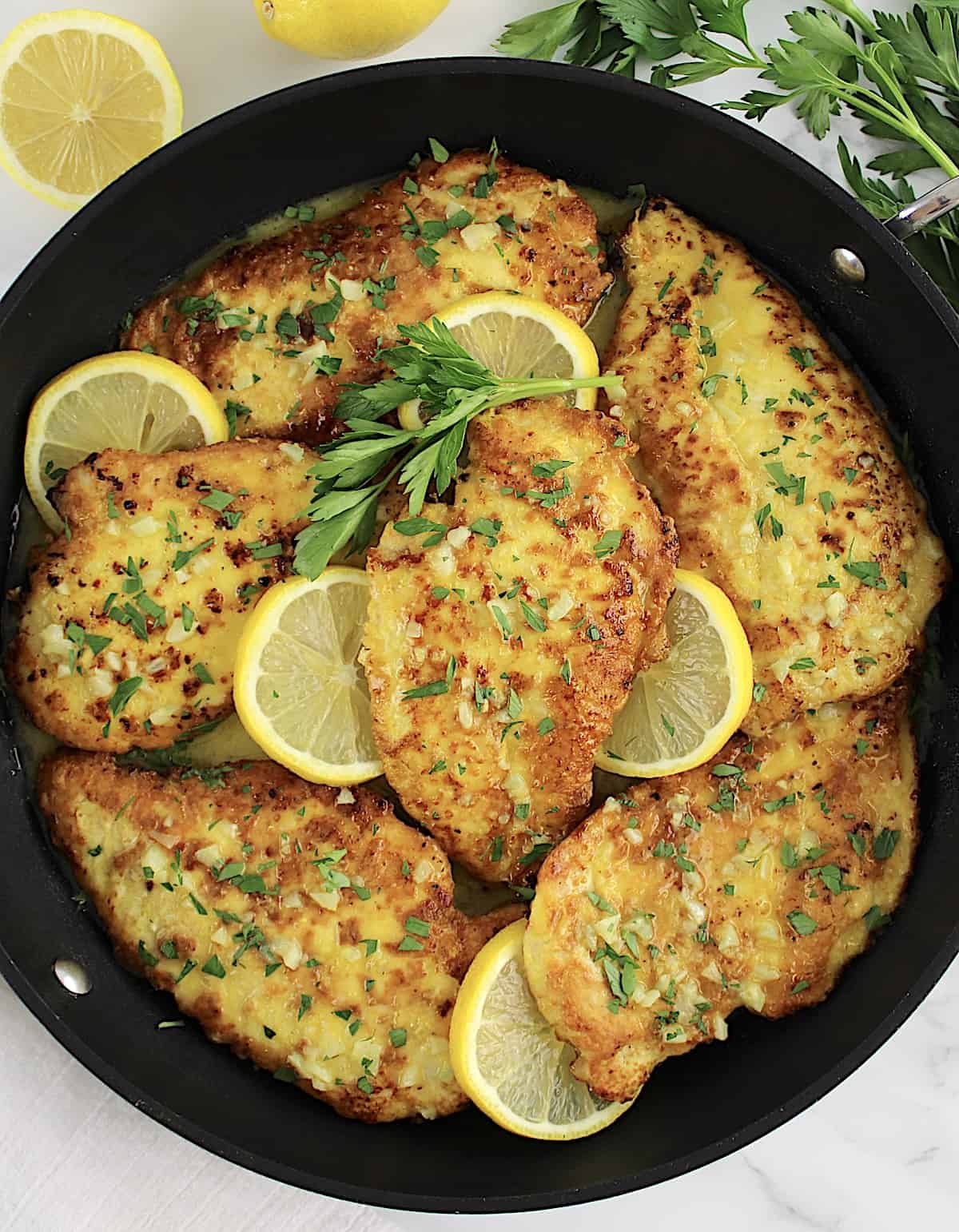 Keto Chicken Francese in skillet with lemon slices and chopped parsley