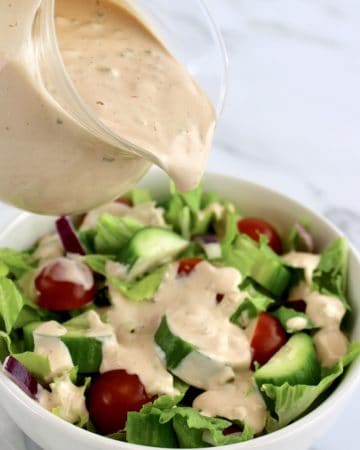 Thousand Island Dressing being poured over a salad
