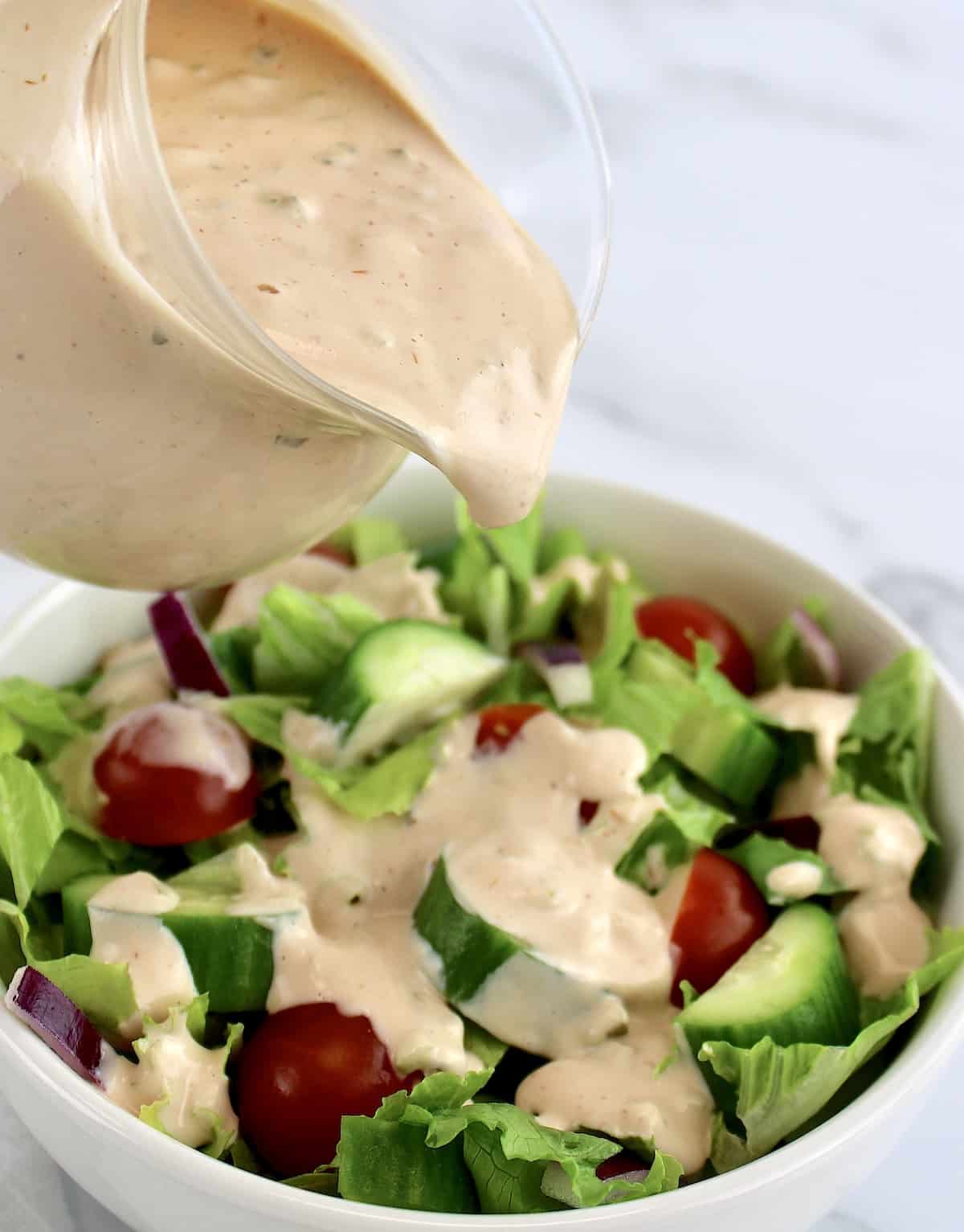 Thousand Island Dressing being poured over a salad