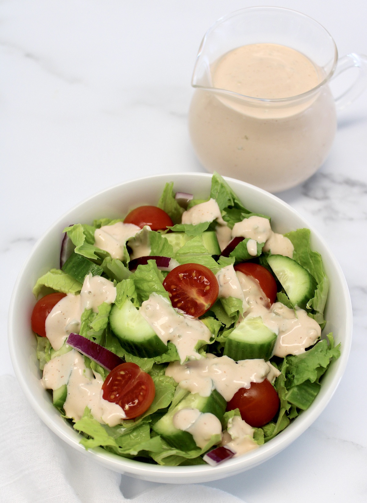 salad with Thousand Island Dressing with dressing in glass pitcher in background
