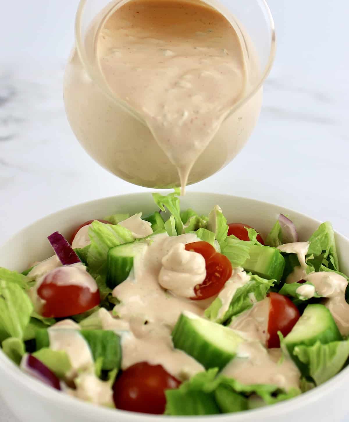 Thousand Island Dressing being poured over salad