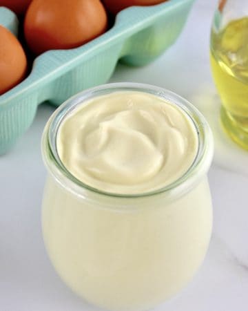 Easy Homemade Keto Mayonnaise in open glass jar with eggs and oil in background