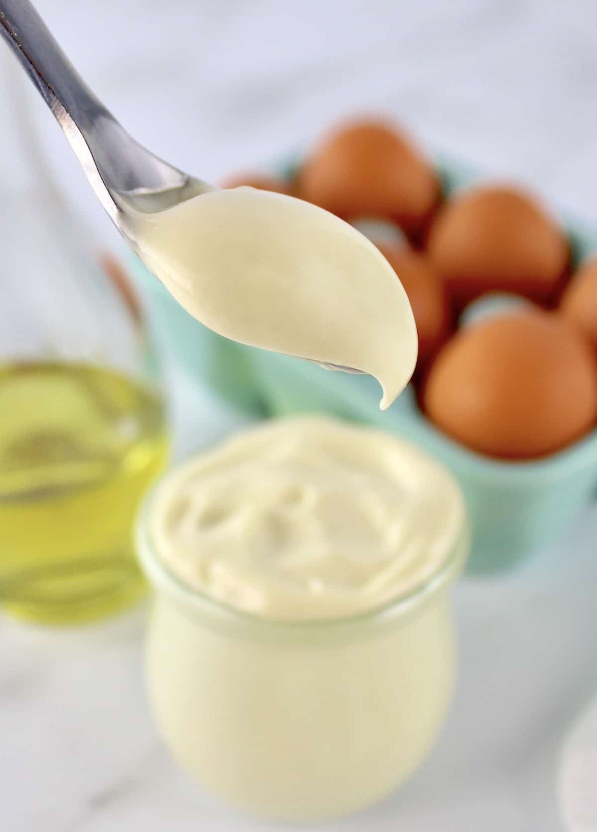 Easy Homemade Keto Mayonnaise being spooned out of open glass jar