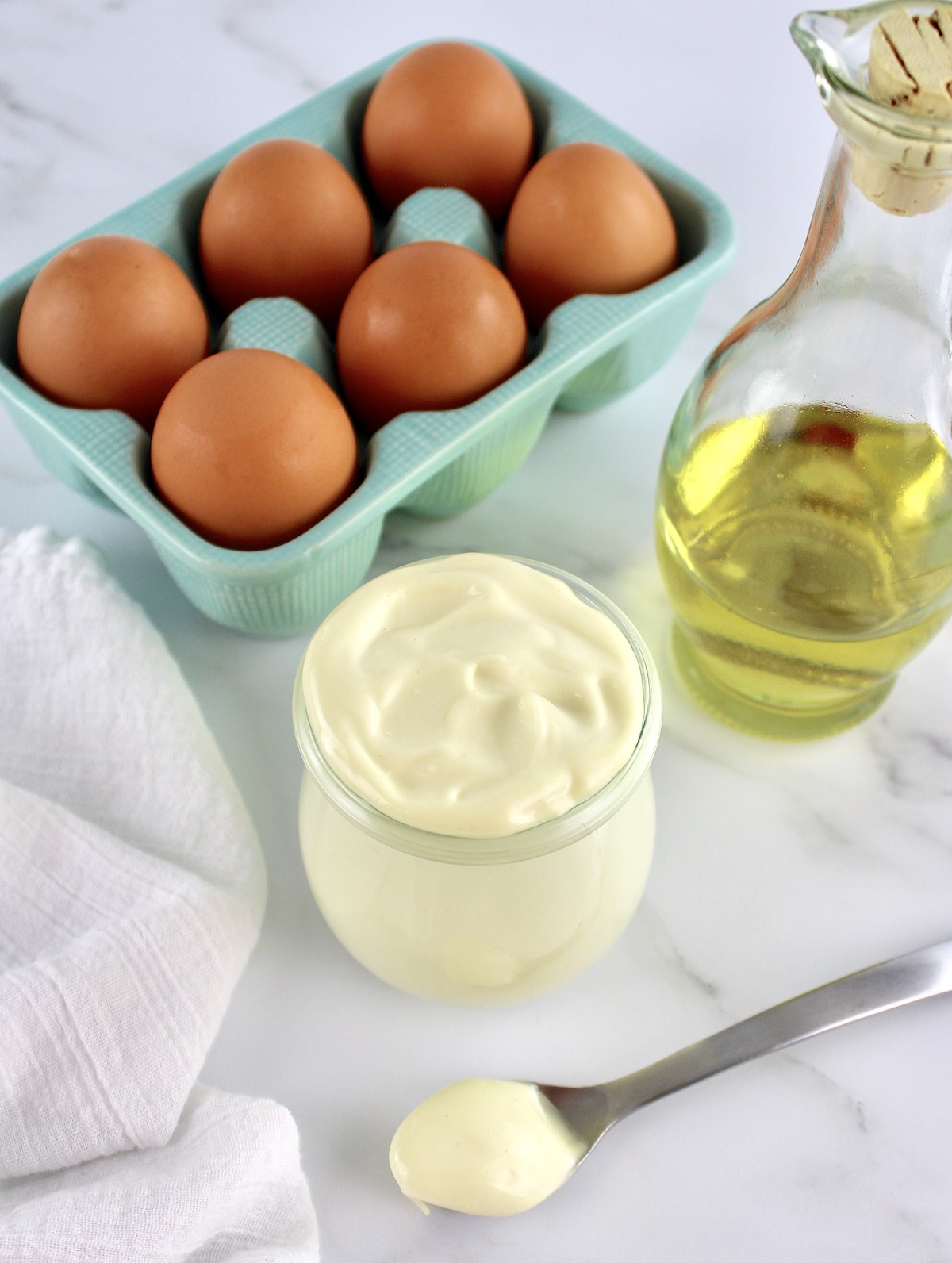 overhead view of Easy Homemade Keto Mayonnaise in open glass jar with eggs and oil in background