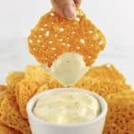 Keto Baked Cheese Crisp Cracker being dipped into dip