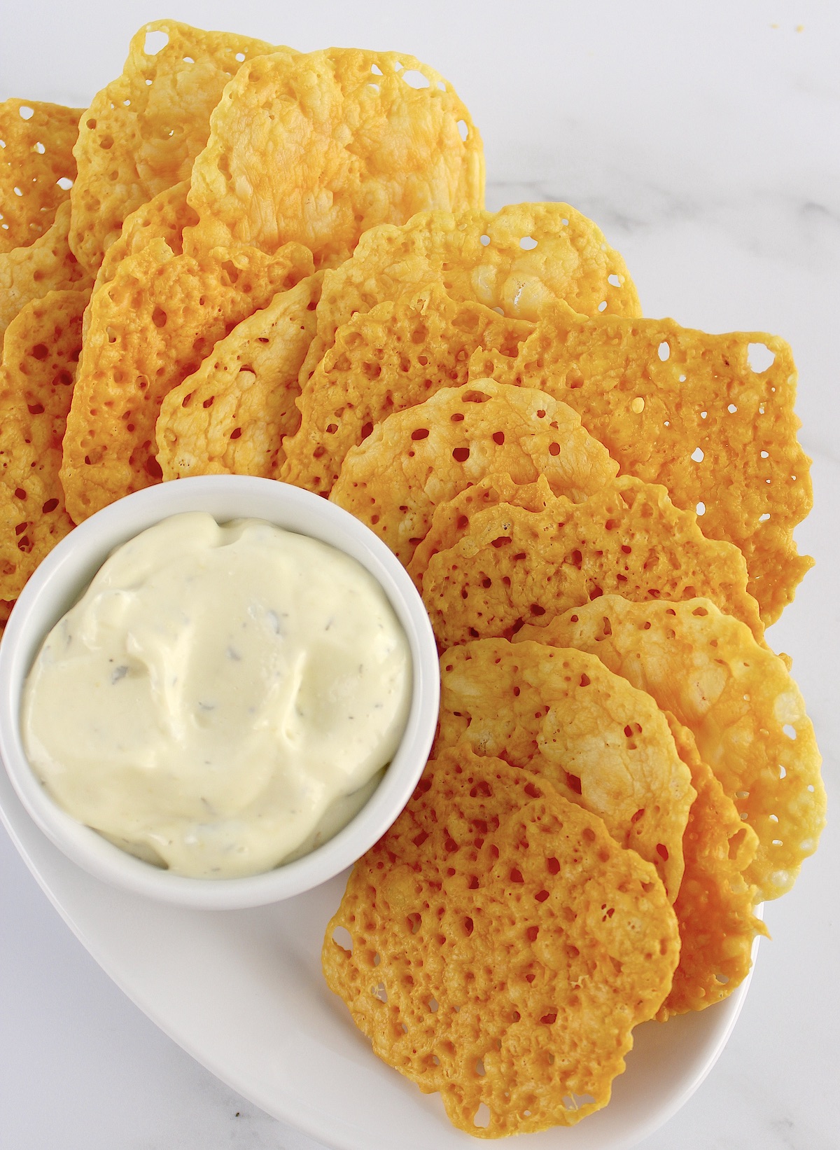 Keto Baked Cheese Crisp Crackers on white plate with ranch dip