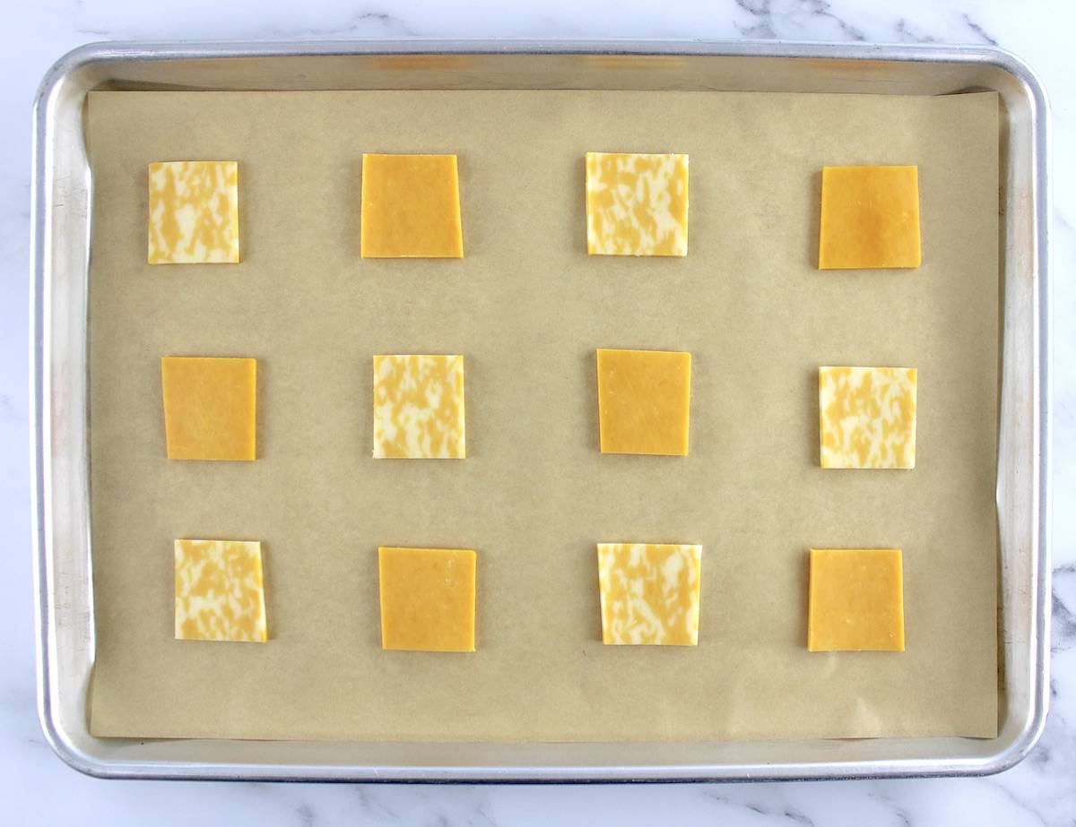 12 cheese slices on parchment lined baking sheet