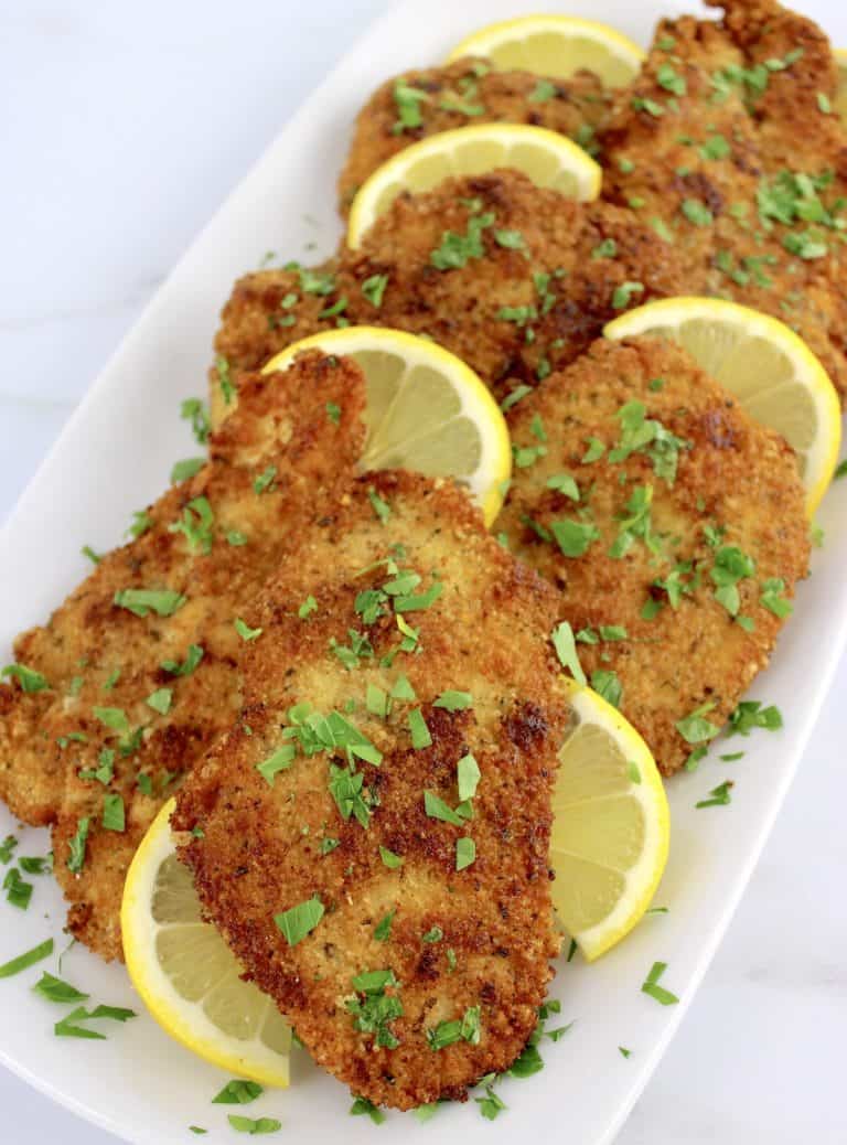 Keto Chicken Milanese on white plate with lemon slices