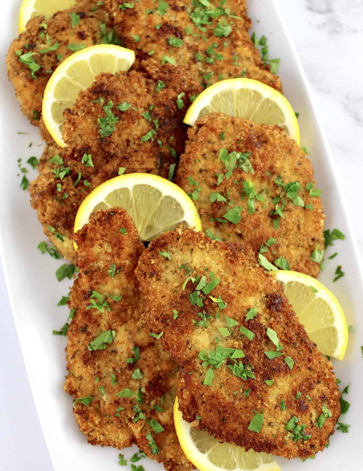 Keto Chicken Milanese on white plate with lemon slices