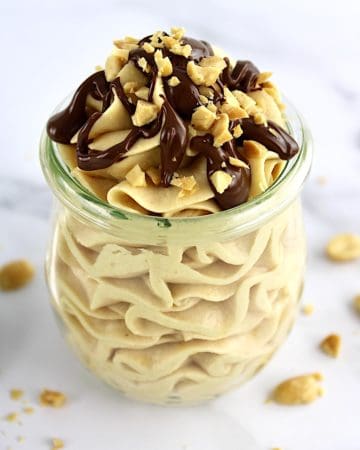 Peanut Butter Mousse in glass open jar with chocolate sauce and chopped peanuts on top