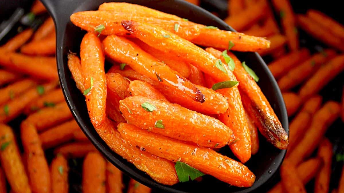 Air Fryer Baby Carrots held up by black serving spoon