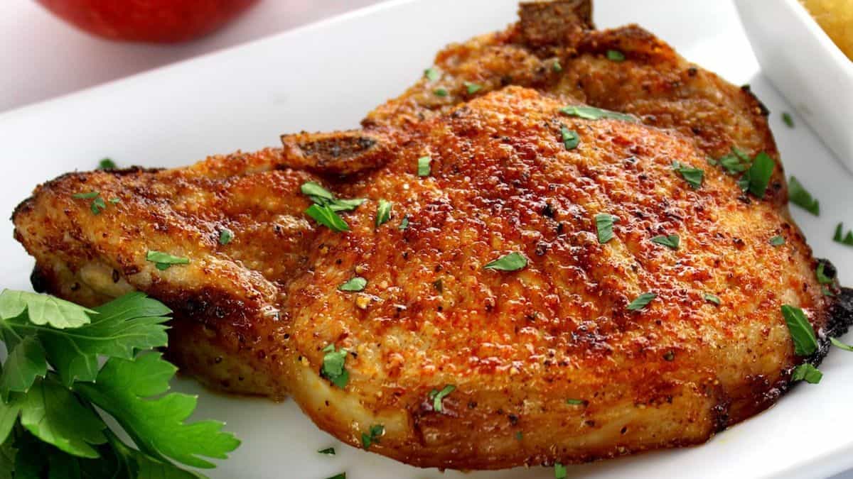 Air Fryer Bone in Pork Chop on white plate with chopped parsley on top