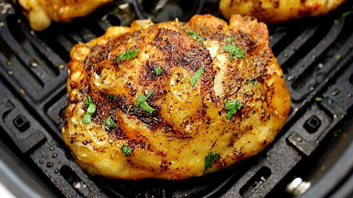 Air Fryer Chicken Thigh in air fryer basket with chopped parsley