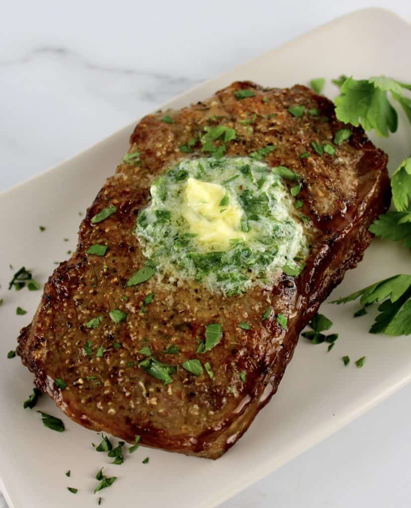Air Fryer Steak with herb butter on top of white plate with parsley