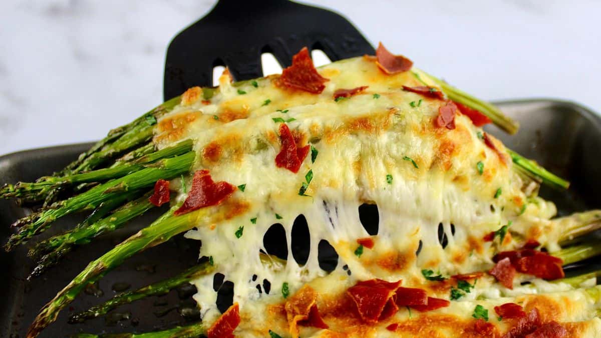 Cheesy Roasted Asparagus with spatula pulling the cheese