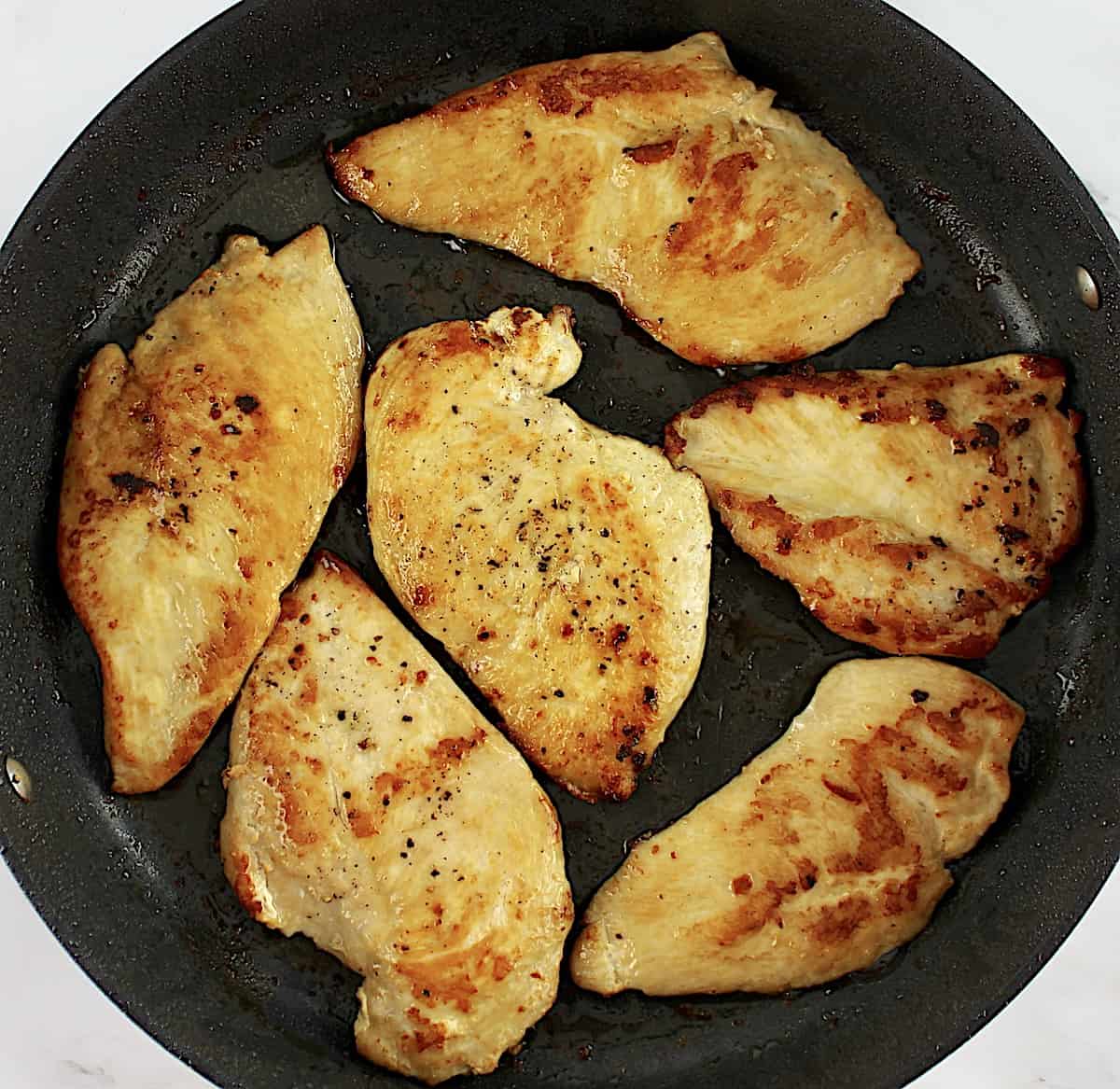 6 chicken breast cooking in skillet