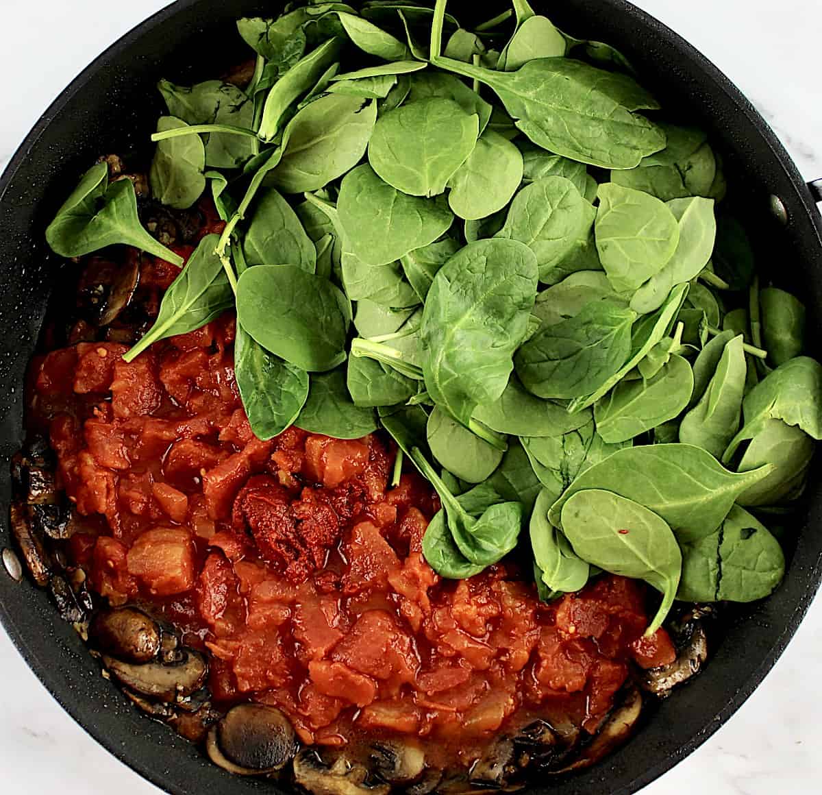 diced tomatoes and baby spinach in skillet