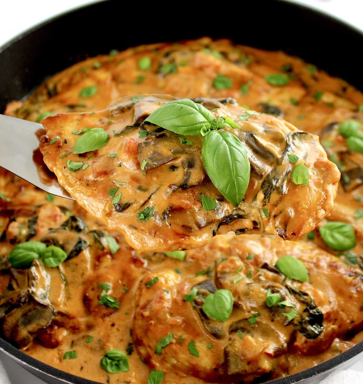 Creamy Tuscan Chicken Skillet held up with spatula