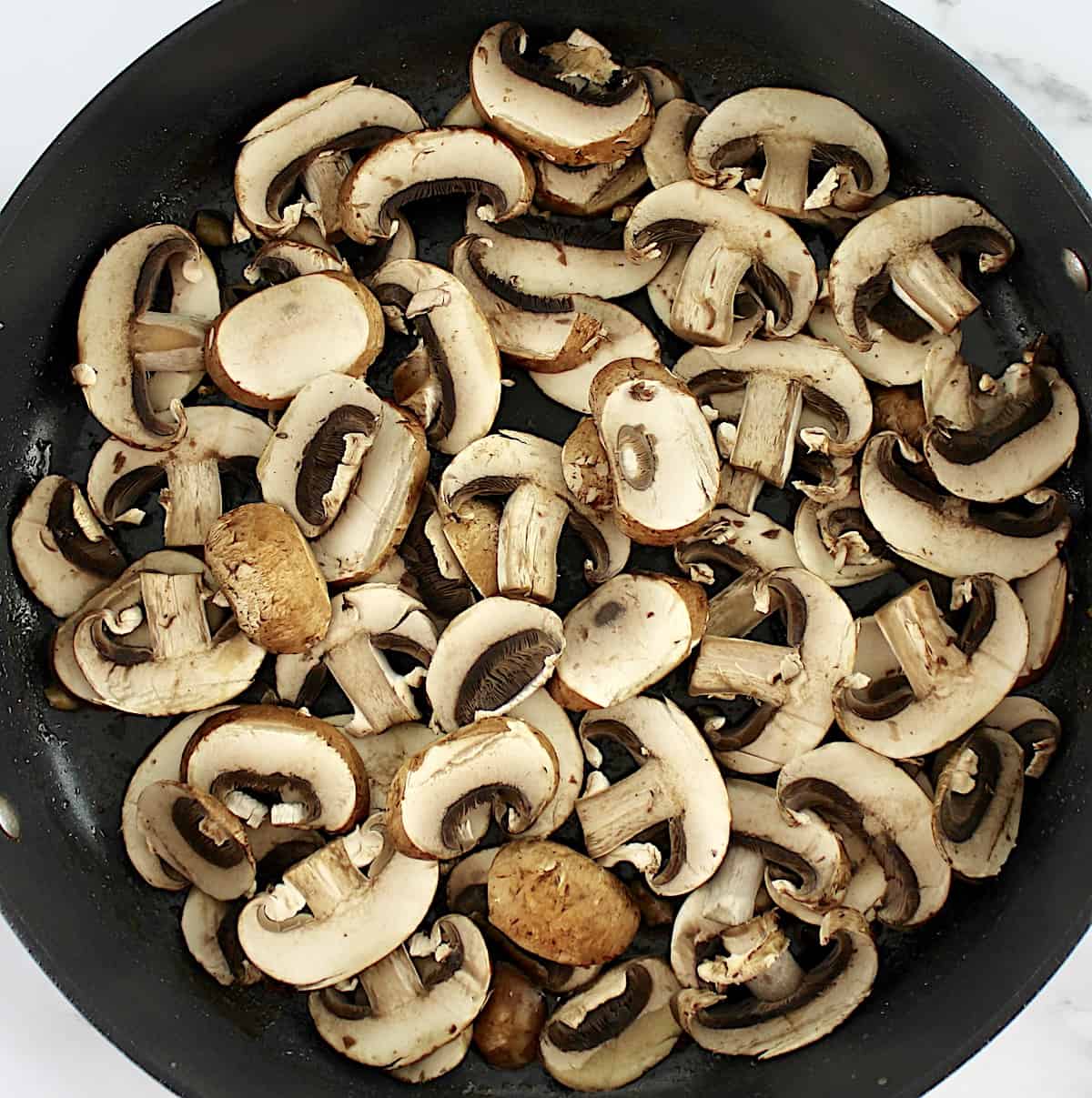 raw sliced mushrooms in skillet