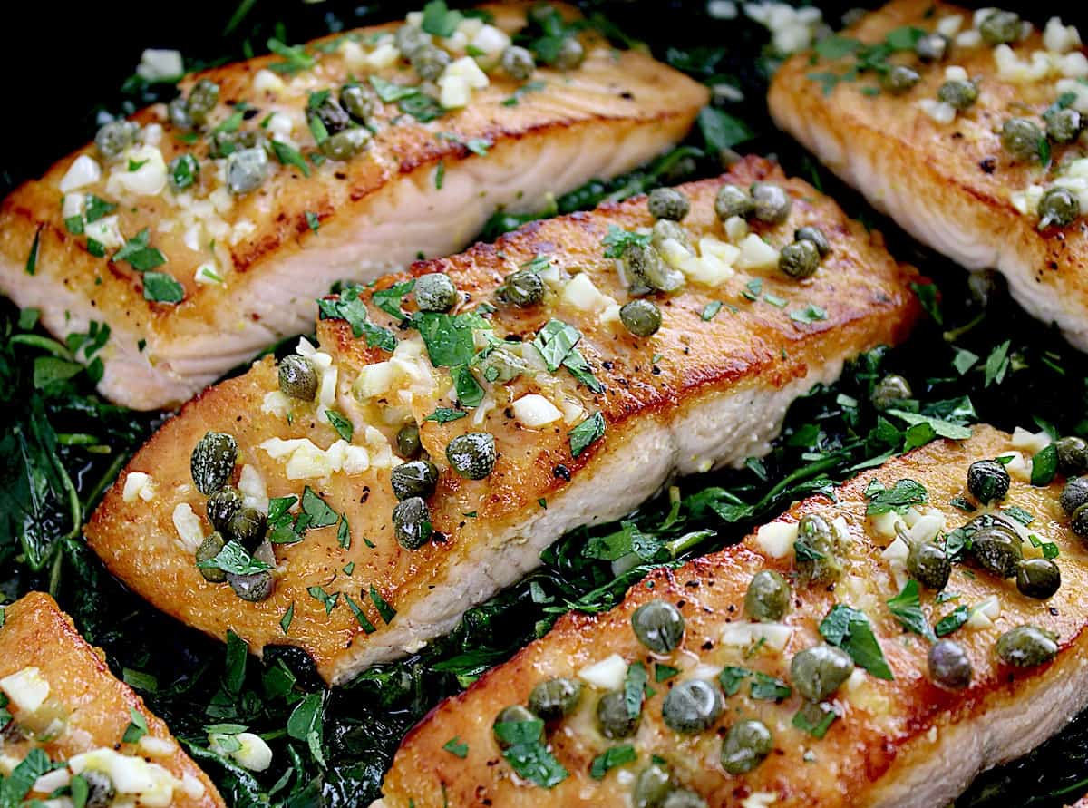 closeup of Salmon Piccata with Spinach in skillet
