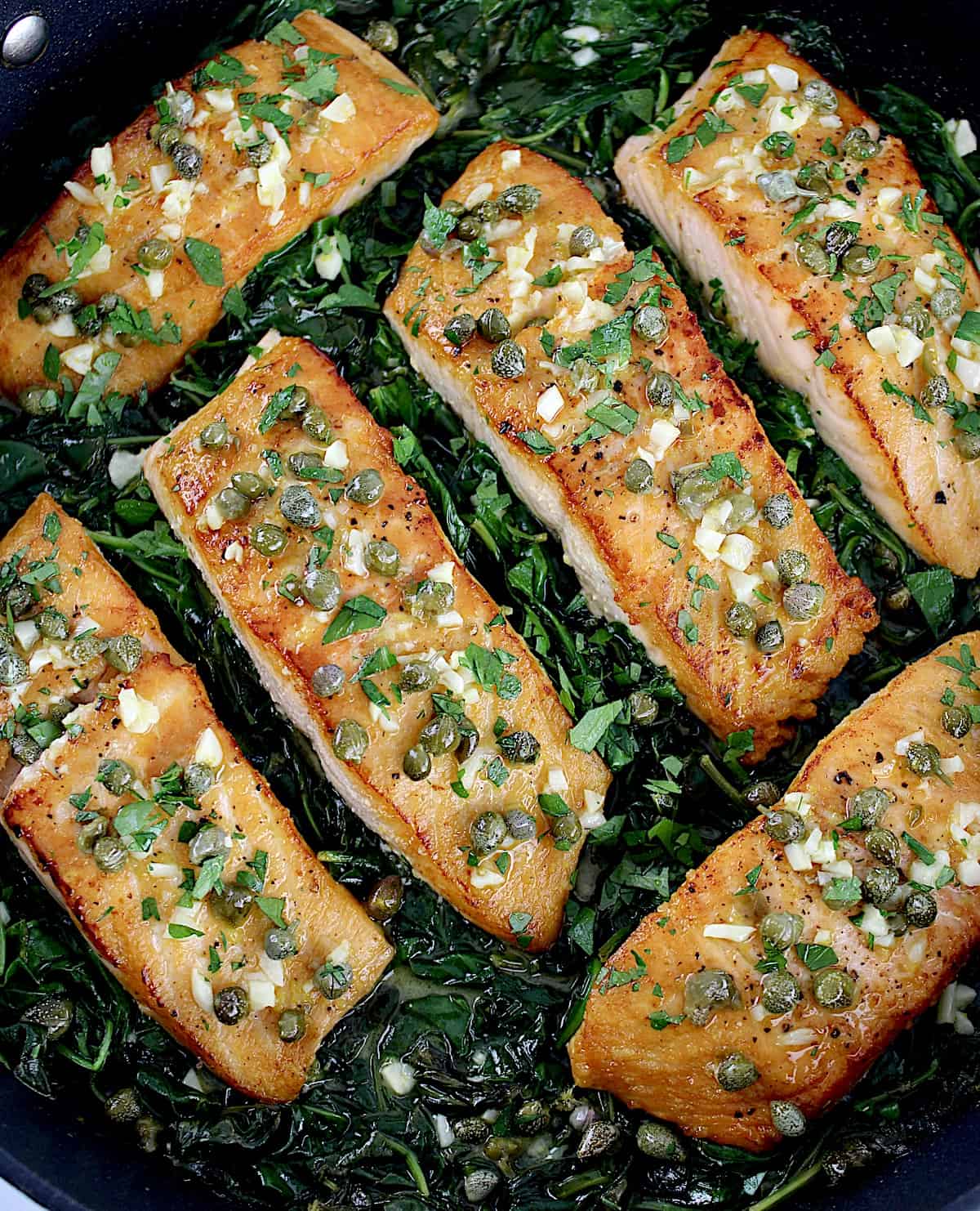 overhead view of Salmon Piccata with Spinach in skillet