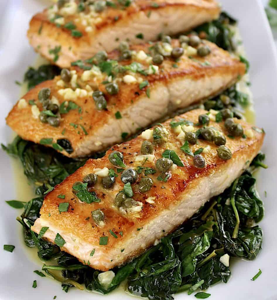 Salmon Piccata with Spinach on white plate