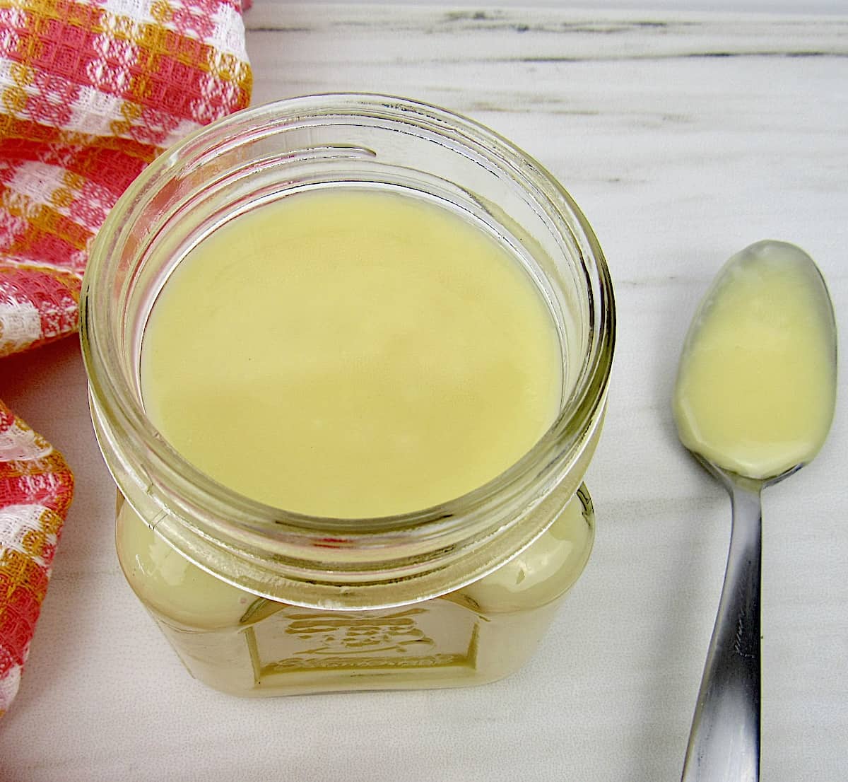 Keto Sweetened Condensed Milk in open jar with spoonful on side