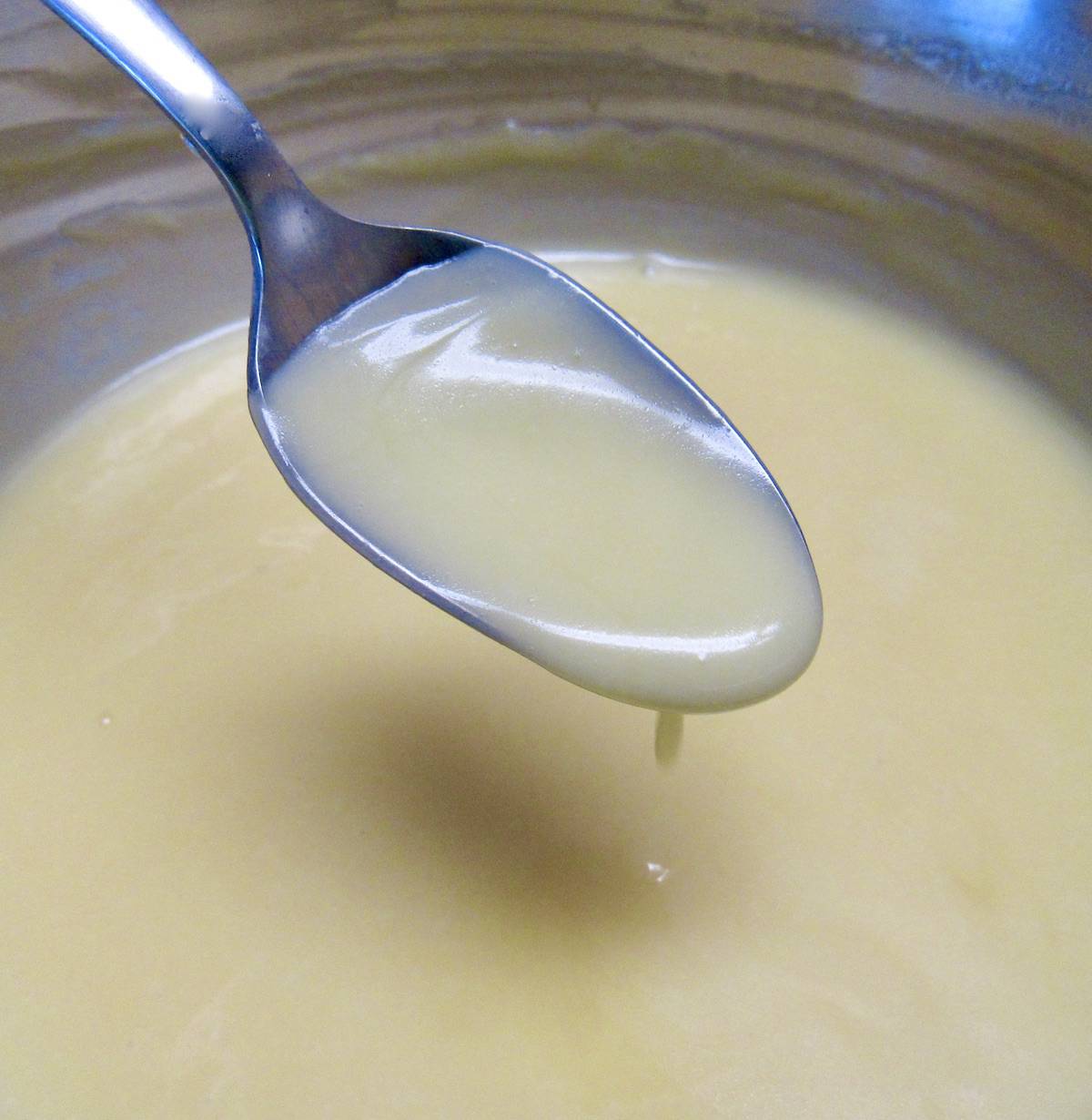 Keto Sweetened Condensed Milk in saucepan dripping off spoon