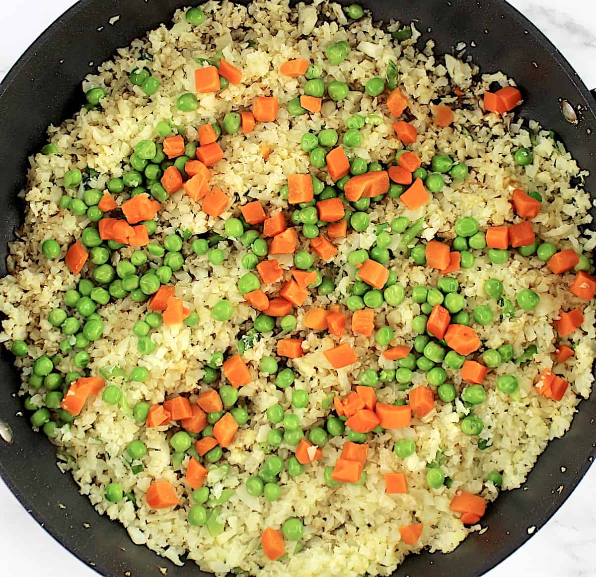 peas, carrots and cauliflower rice in skillet