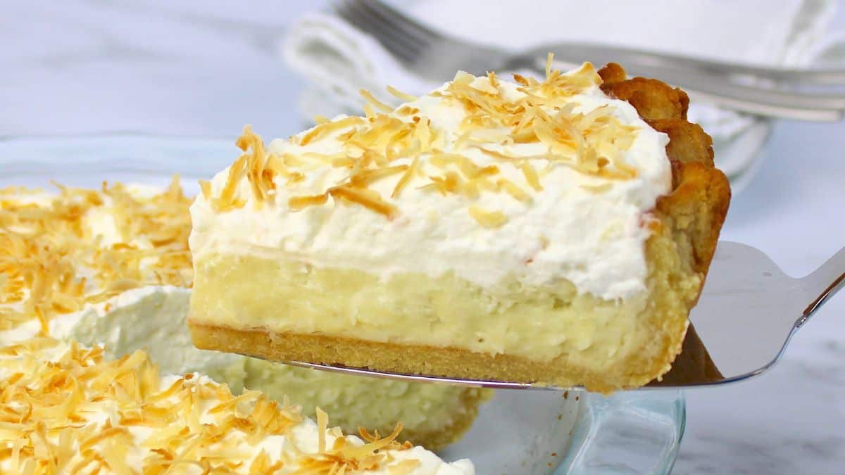 slice of coconut cream pie held up with silver cake server