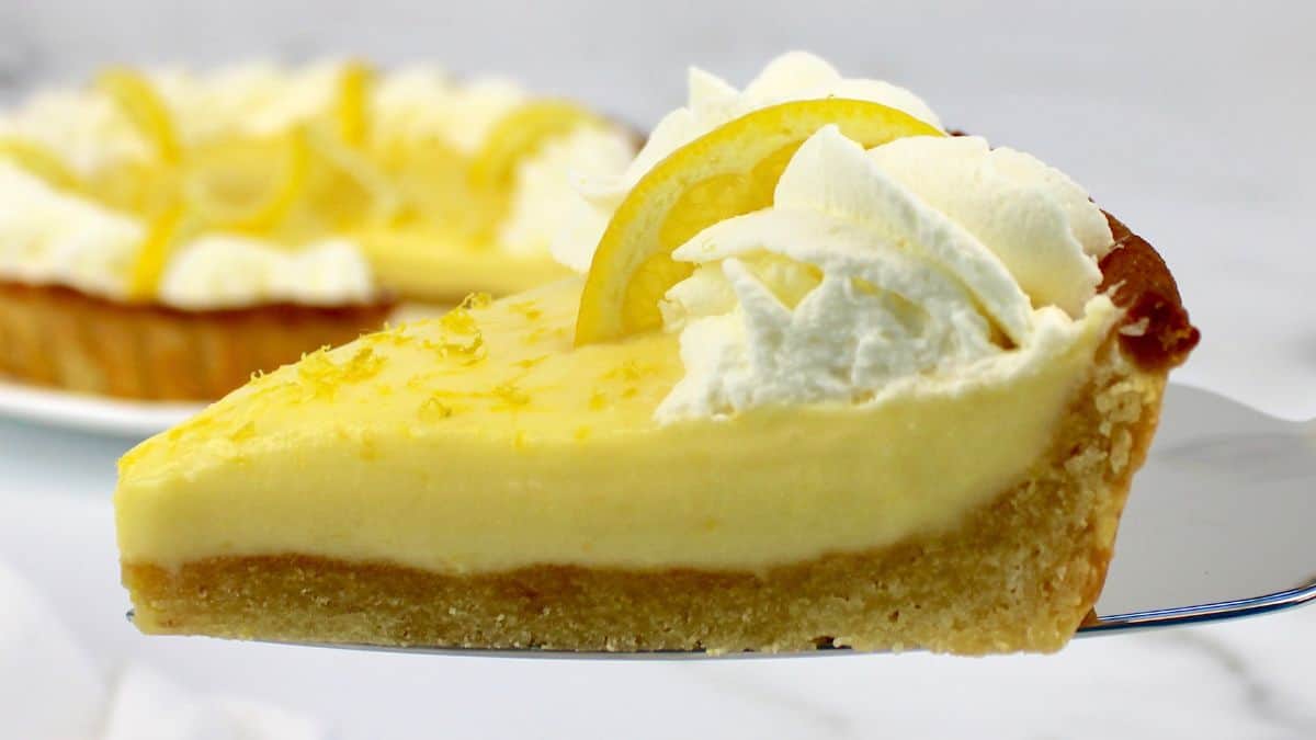 closeup of slice of lemon mascarpone tart with whip cream and lemon on top