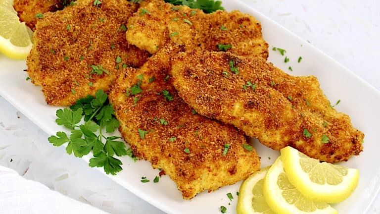 Air Fryer Cod on white plate with lemon slices and fresh parsley