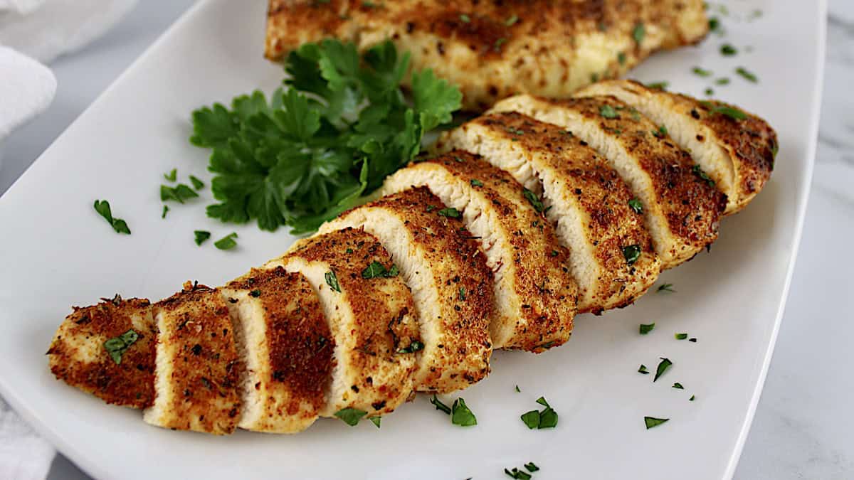 air fryer italian seasoned chicken sliced on white plate with parsley