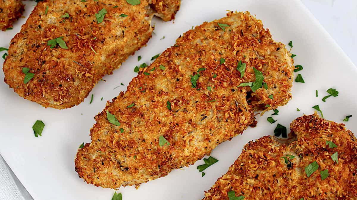 closeup of Air Fryer Pork Chops on white plate with chopped parsley