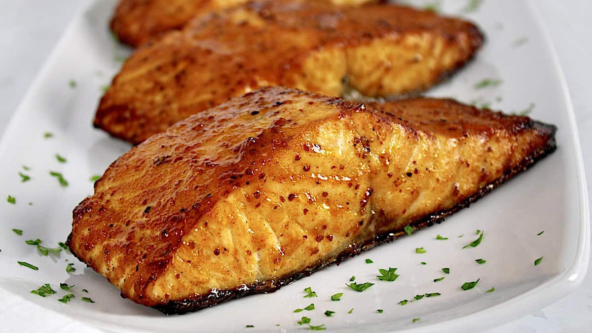 Air Fryer Salmon pieces on white plate with chopped parsley