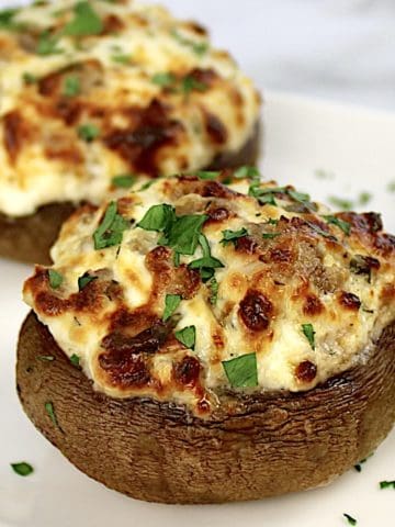 closeup of Air Fryer Stuffed Mushrooms on white plate with chopped parsley