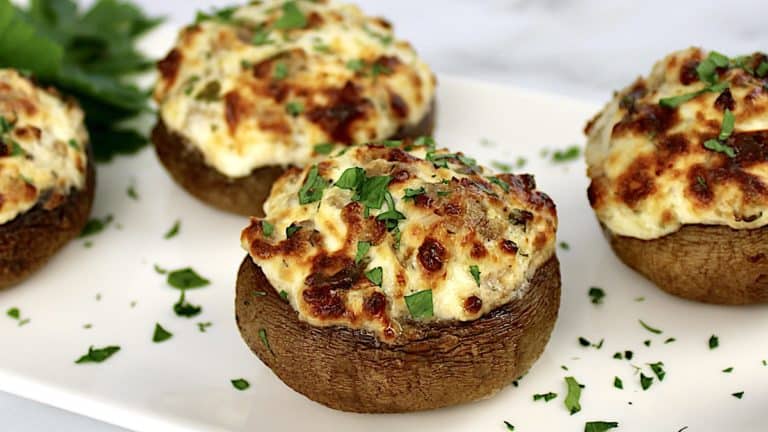 closeup of Air Fryer Stuffed Mushrooms on white plate with chopped parsley